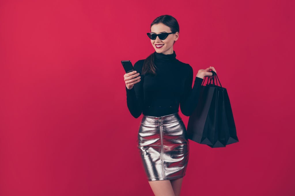 Portrait of her she nice-looking attractive pretty trendy cheerful lady using cell carrying, black bags order online new brandy things isolated over maroon burgundy marsala red pastel color background